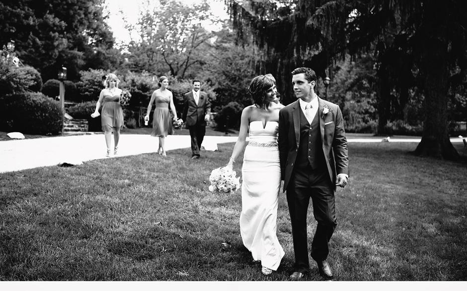 The bride and groom walk the grounds together with the bridal party after their ceremony at Appleford Estate in Villanova